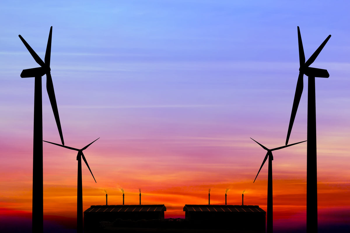Silhouette of wind turbines against a colorful sunset sky, symbolizing renewable energy.
