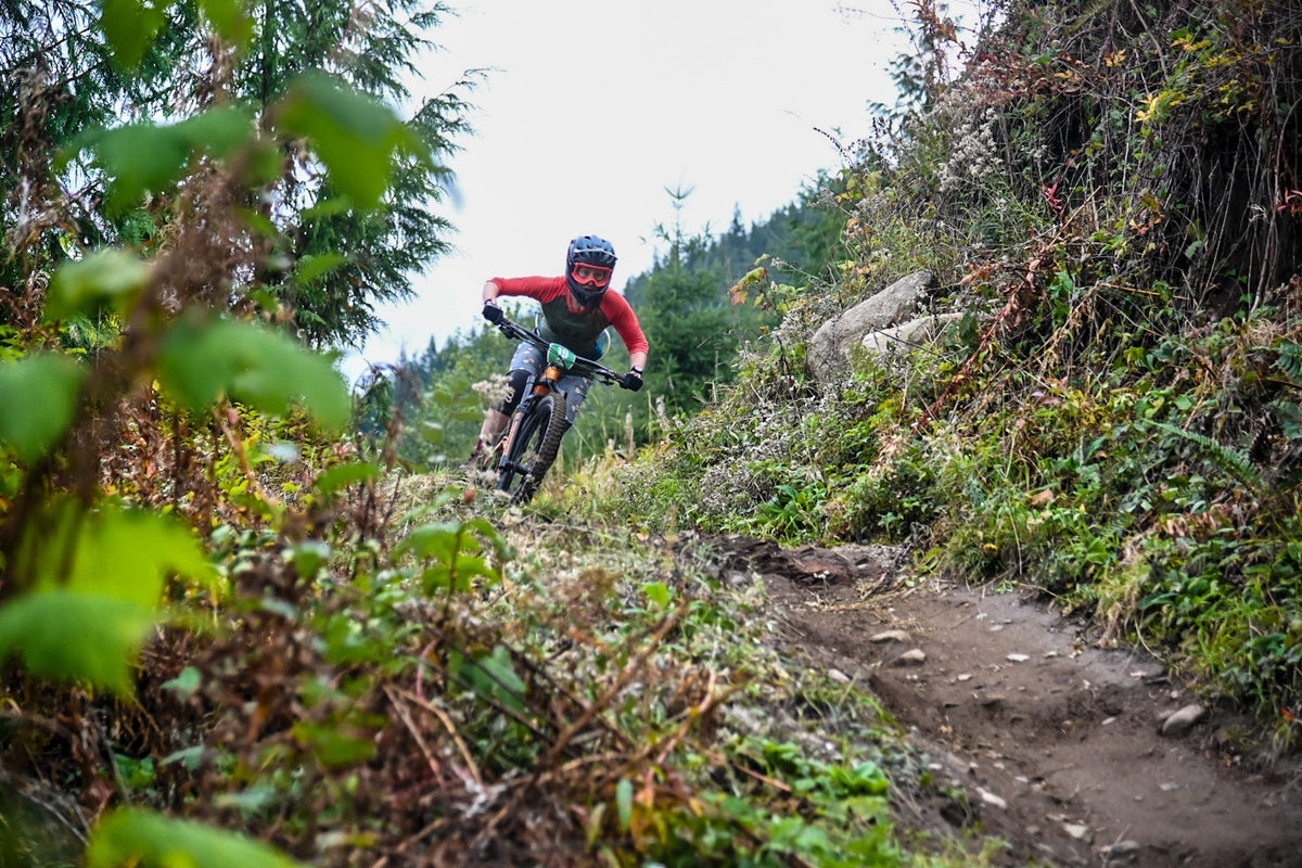 A woman riding a mountain bike on a trail surrounded by greenery.