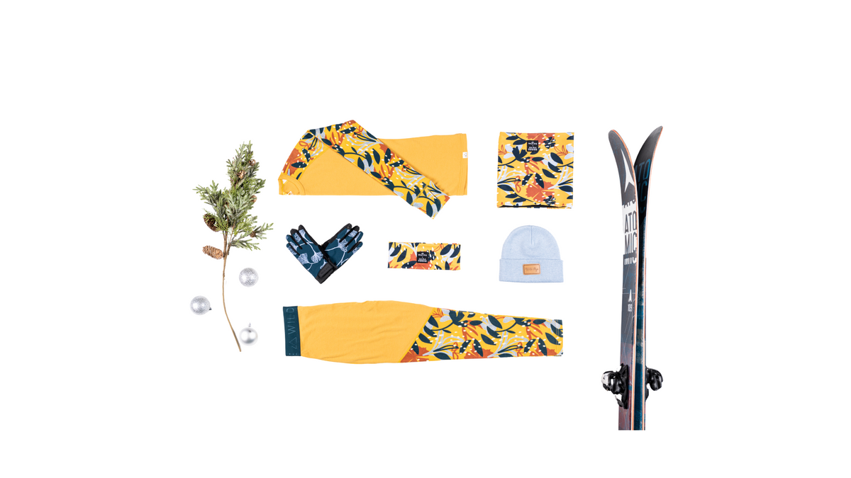 Flat lay of ski apparel and accessories including gloves, a beanie, and ski gear.