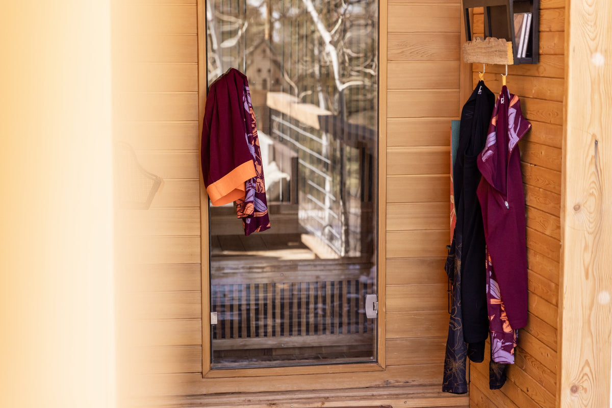 A wooden entryway with colorful clothing hanging on hooks
