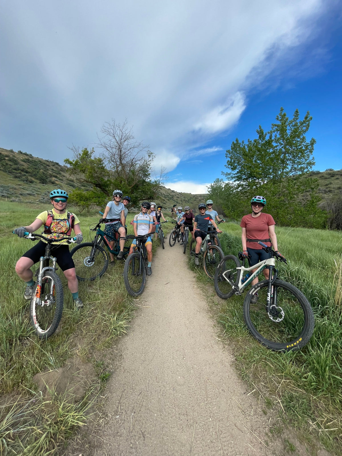 Group of cyclists on a trail in Boise, surrounded by greenery and hills.