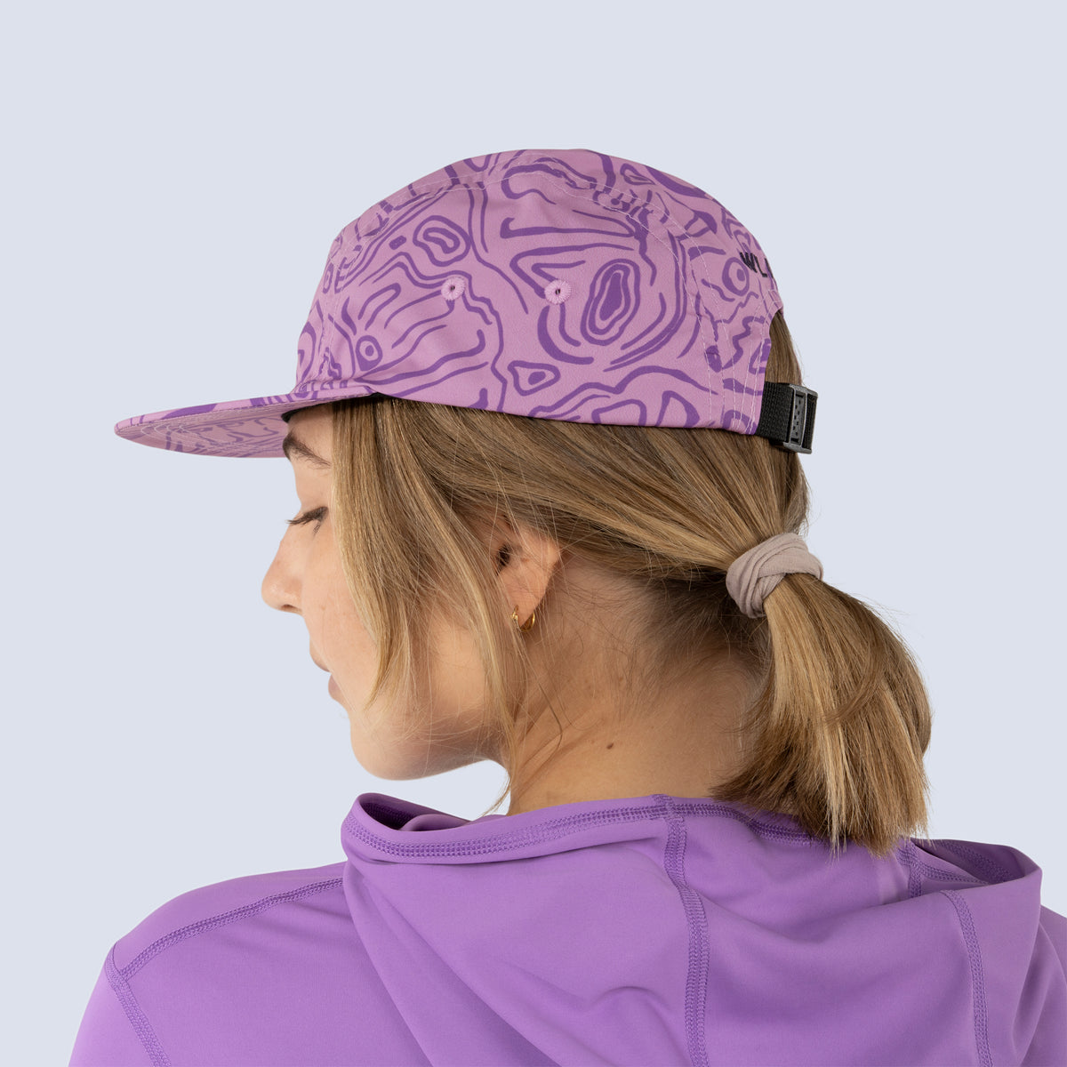 Person wearing a pink baseball cap and purple shirt, back view