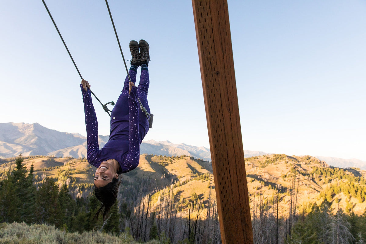 Person zip lining in a mountainous landscape during sunset