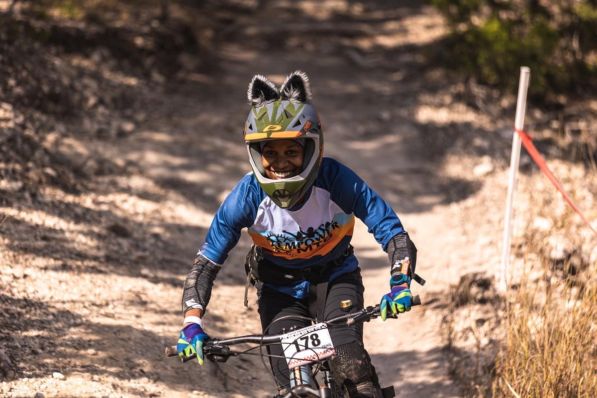 Aja Jackson riding a mountain bike on a trail, wearing a helmet with ears and race number 178.