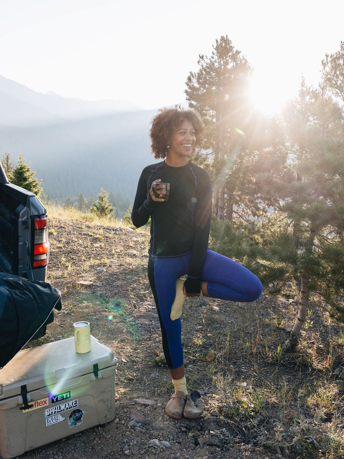 [Lapis Blocked] Bassett LITE Legging in lapis blocked, on model adjusting gear at a mountain campsite shot