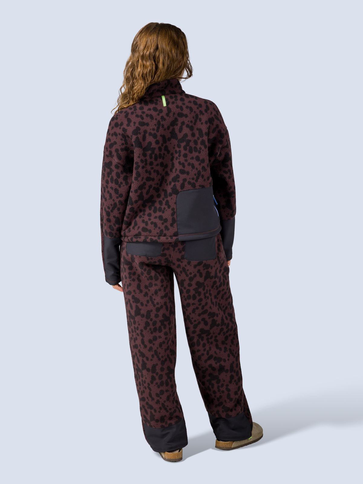 [Dapple] Model wearing the Banner 3/4 Zip Jacket in brown leopard-print fleece with matching lounge pants, full back view