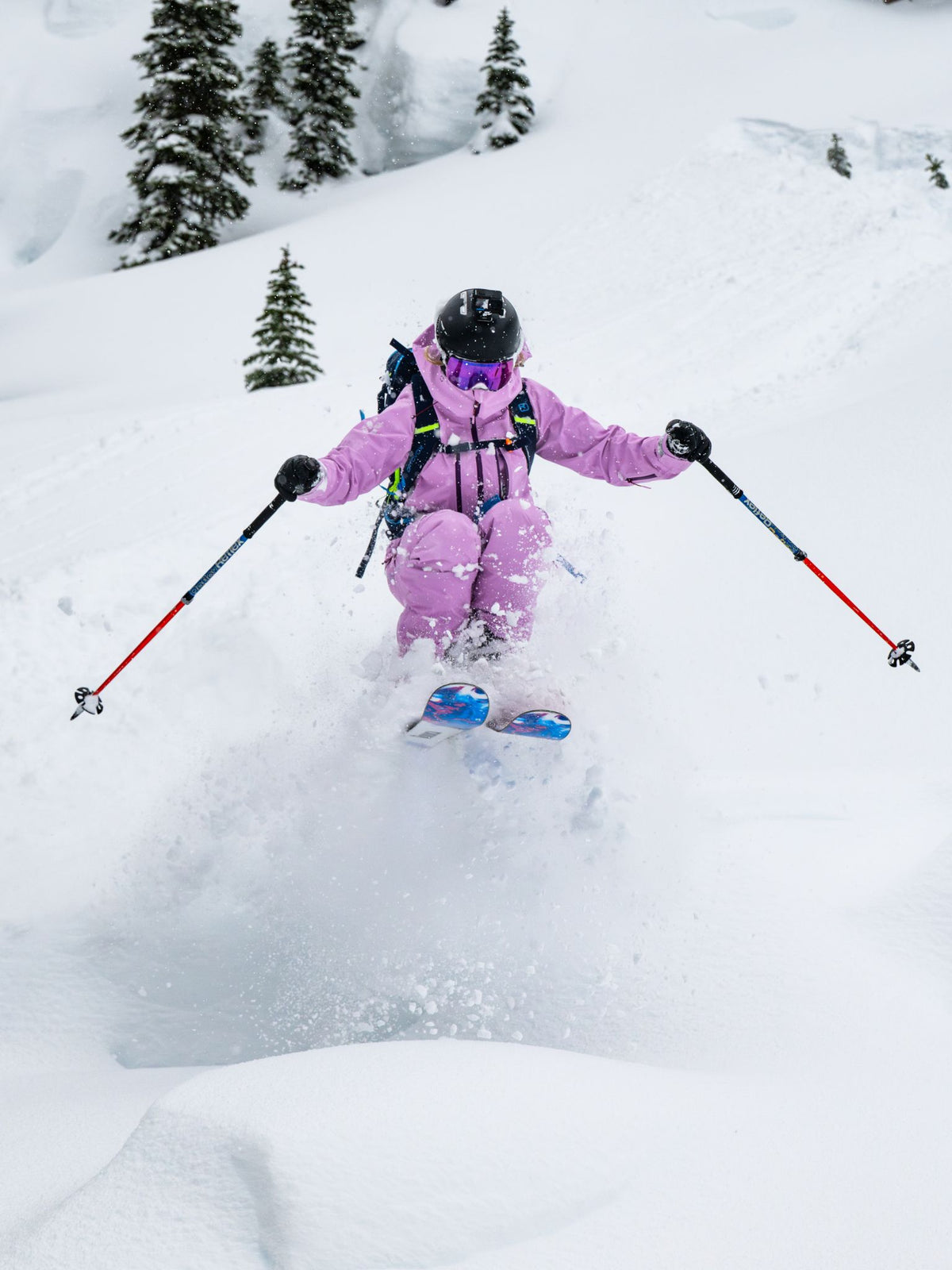 [Orchid] Woman skiing through deep powder in an orchid pink Heyburn 3L Bib and matching jacket