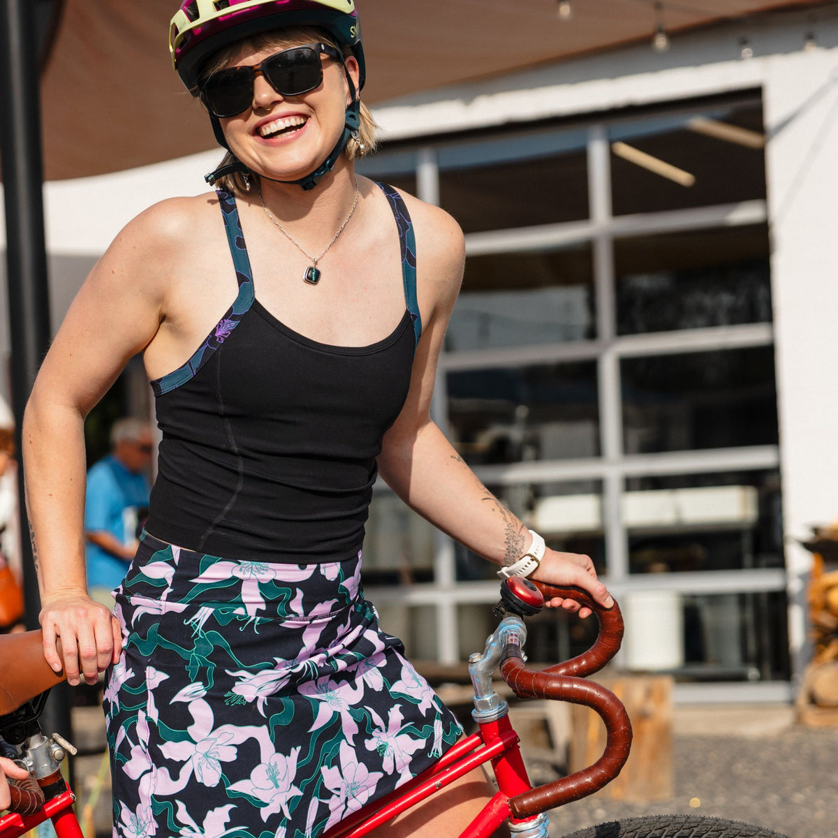 [Black] Woman on a red bicycle wearing a helmet and sunglasses, with a blurred background