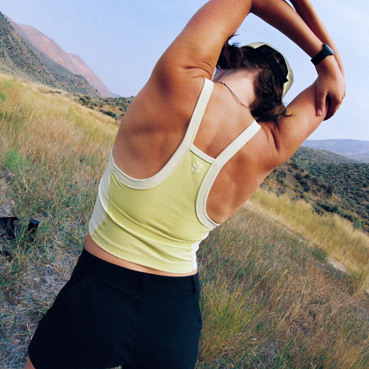 [Gecko Blocked] Person stretching outdoors in a natural setting with mountains in the background