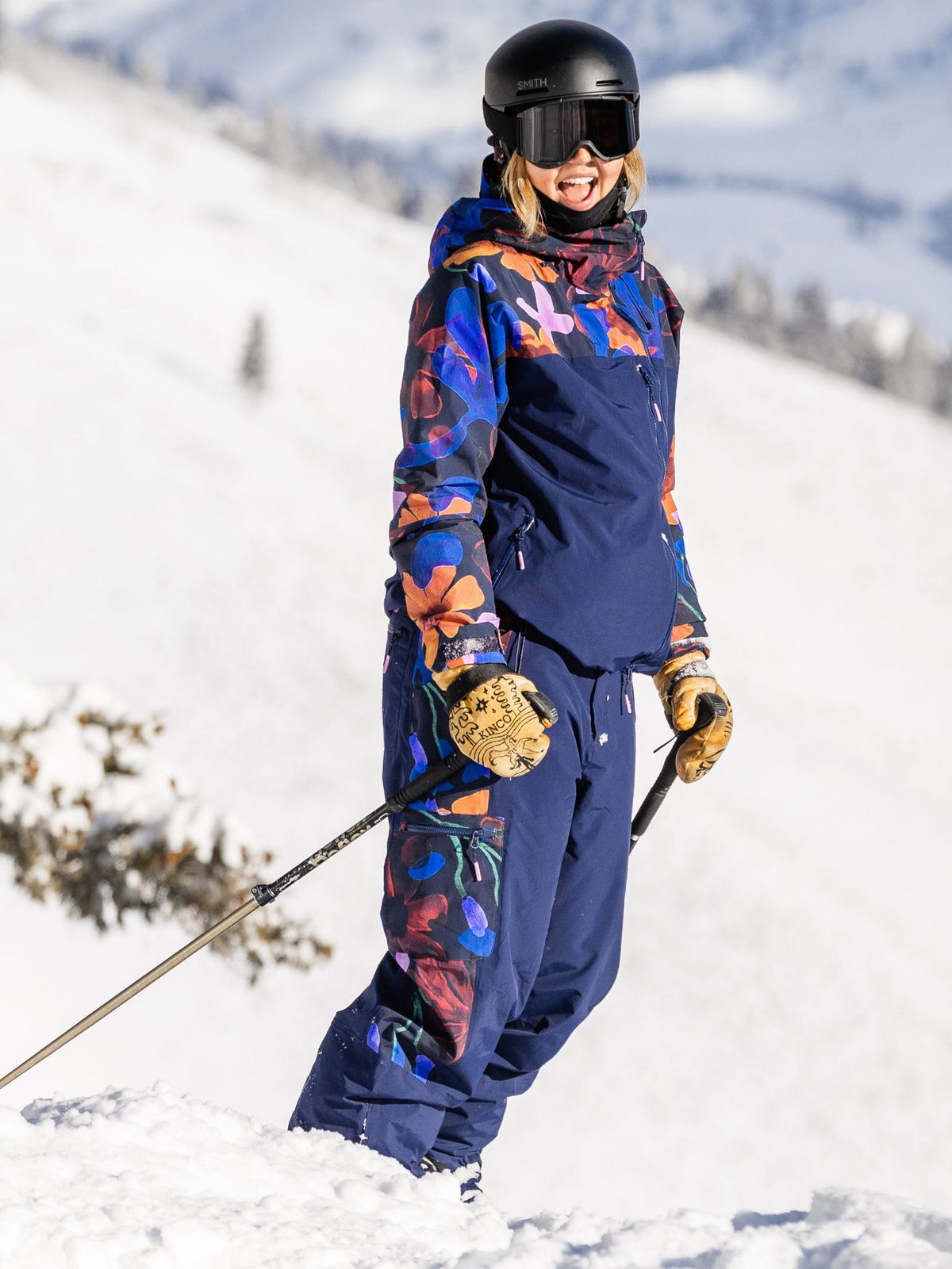 [Nightflora] Woman pausing on a snowy ski slope in a nightflora floral print Roundhouse 2L Insulated Jacket
