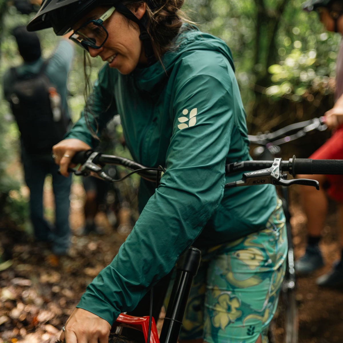 [Shaded Spruce] Person on a mountain bike in a forest setting wearing the shaded spruce rustler jacket