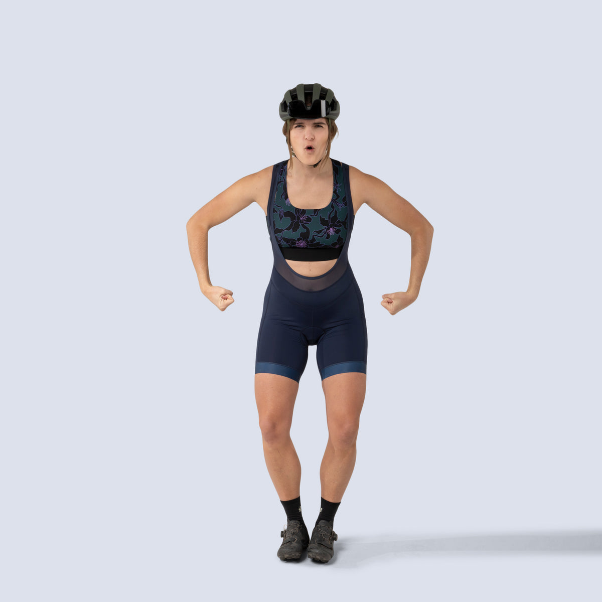 [Spruce Aquila Bloom] Lucille sports bra in green with black floral pattern, on model flexing arms