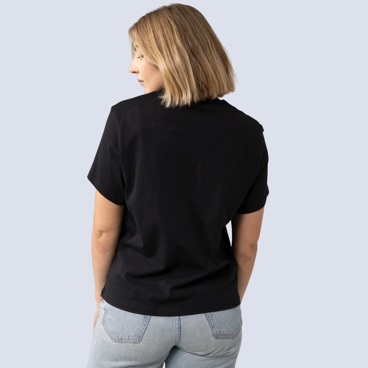 Person wearing a black t-shirt and light blue jeans on a plain background