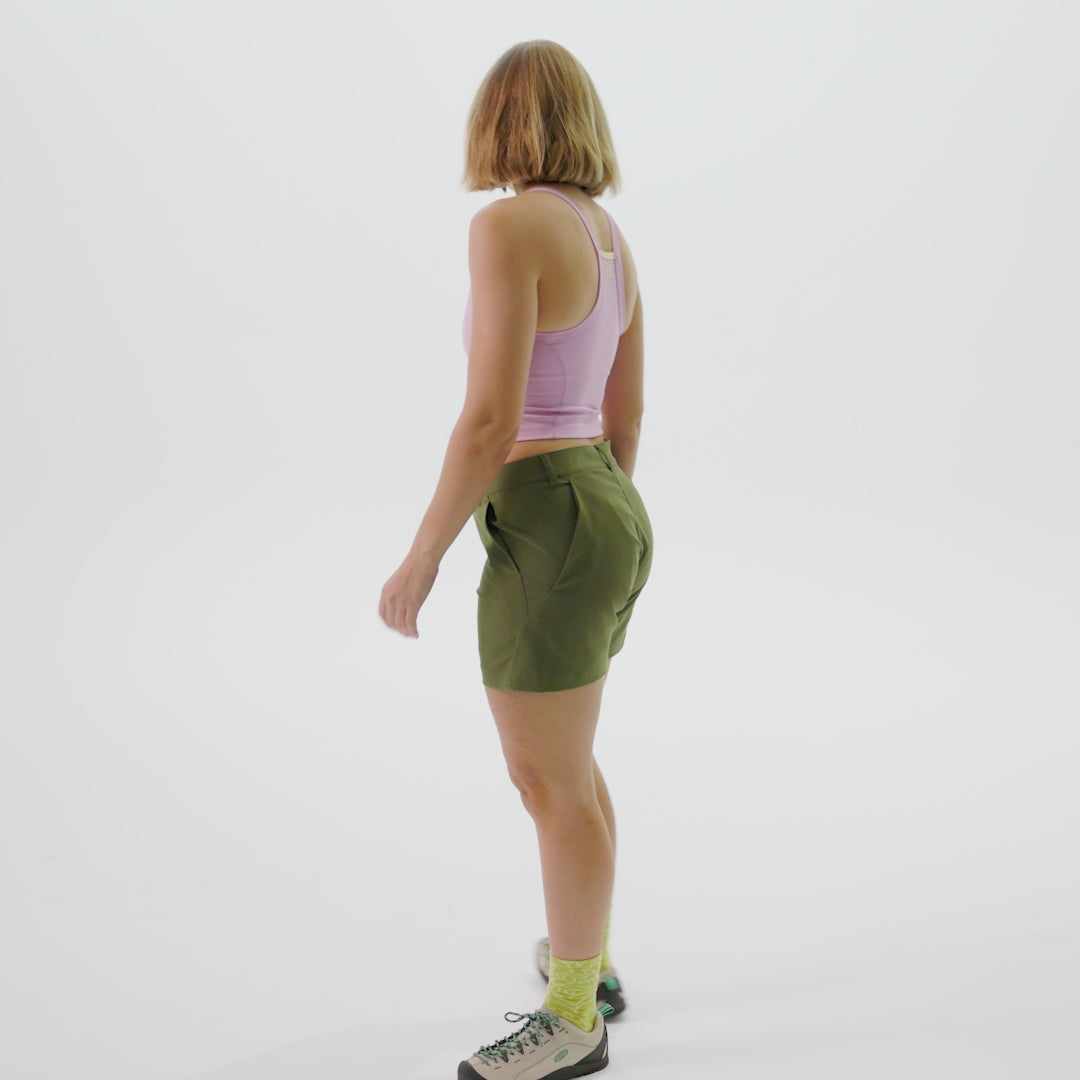 Woman wearing pink tank top and green esther shorts, showing the a-line fit of the shorts and 4 pockets