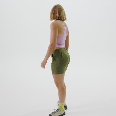 Woman wearing pink tank top and green esther shorts, showing the a-line fit of the shorts and 4 pockets